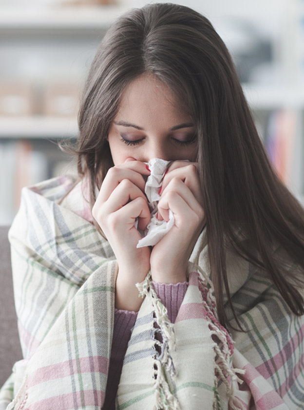 A-Young-Woman-Sneezing-into-a-Tissue-Pape